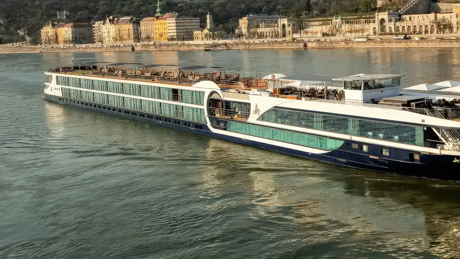 An Avalon Waterways Suite Ship cruising a European river past a riverside town
