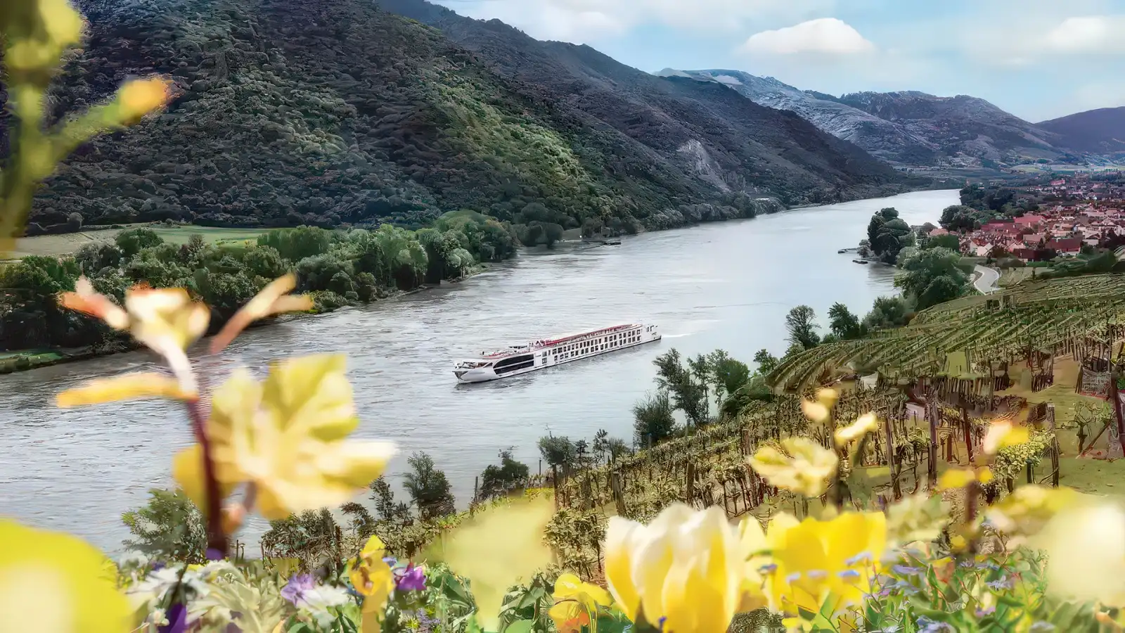 A Uniworld Super Ship moored along a green European riverbank