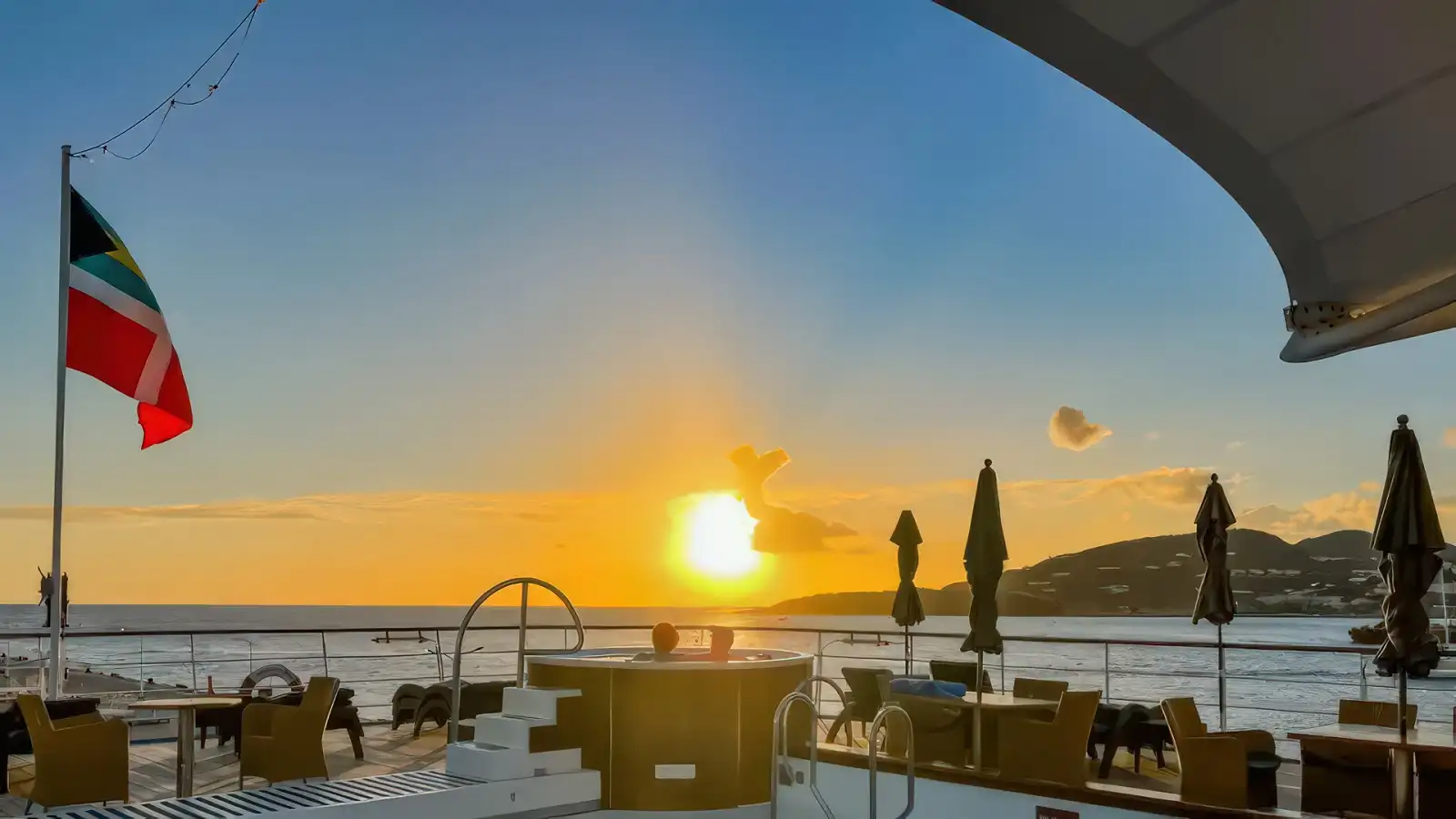 A Windstar sailing yacht with billowing white sails at sunset