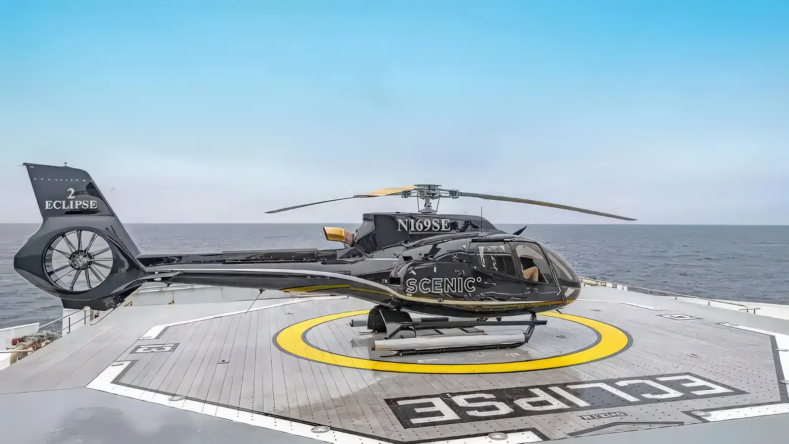 A helicopter lifting off from the deck of Scenic Eclipse over open water