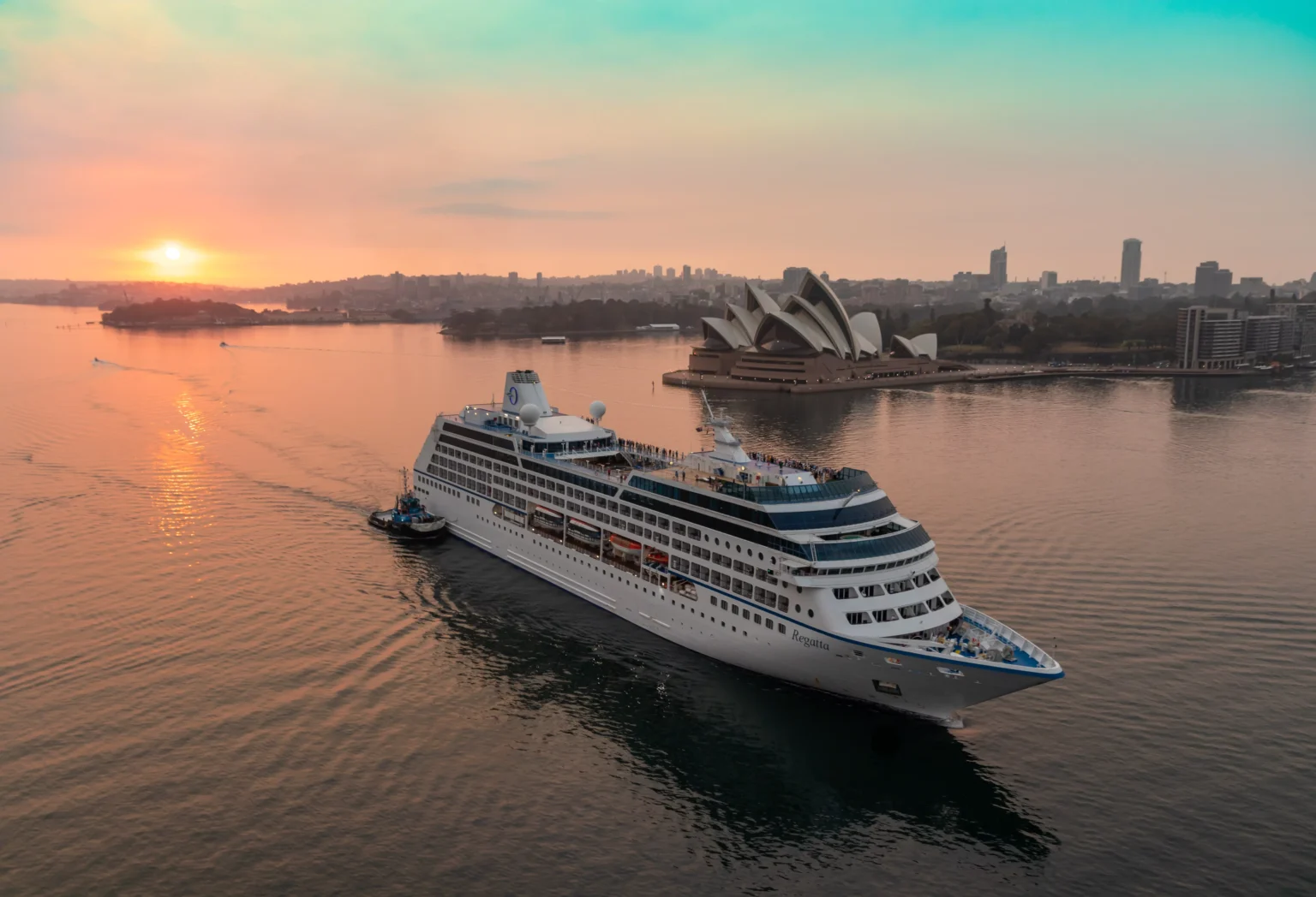 A luxury world-cruise ship at anchor off a dramatic coastline